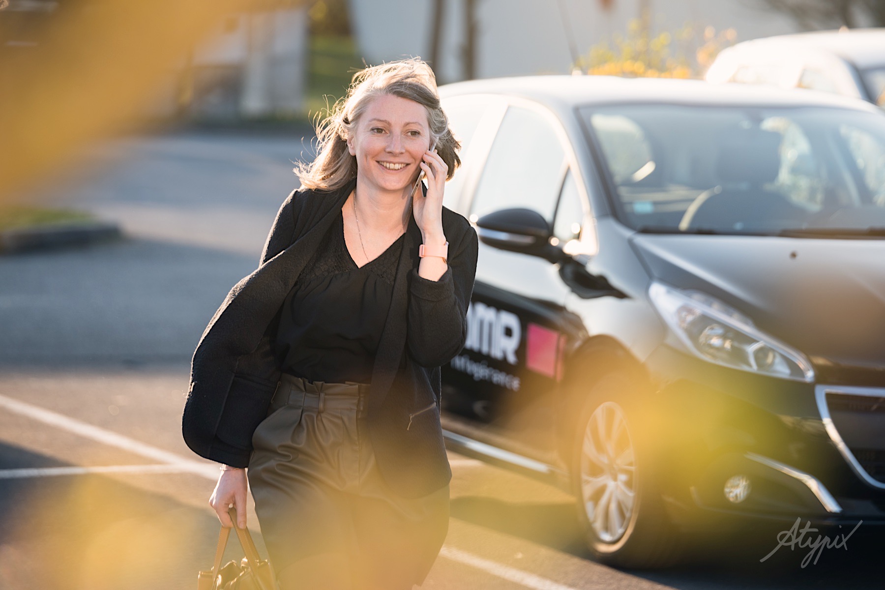femme gérante entreprise au téléphone devant sa voiture de fonction