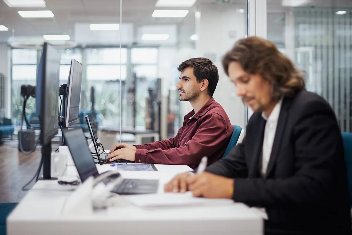 Deux collaborateurs travaillent sur des ordinateurs dans des bureaux modernes
