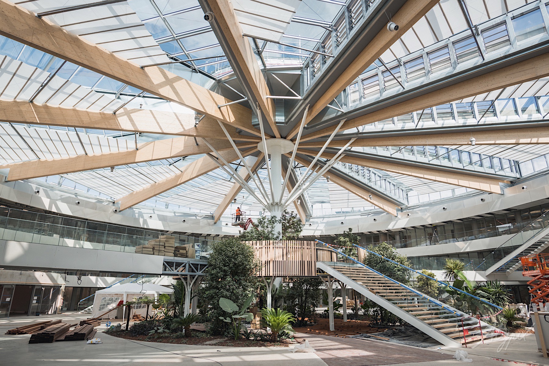Photographie de chantier d’un bâtiment en finition avec charpente bois et verrière intérieure